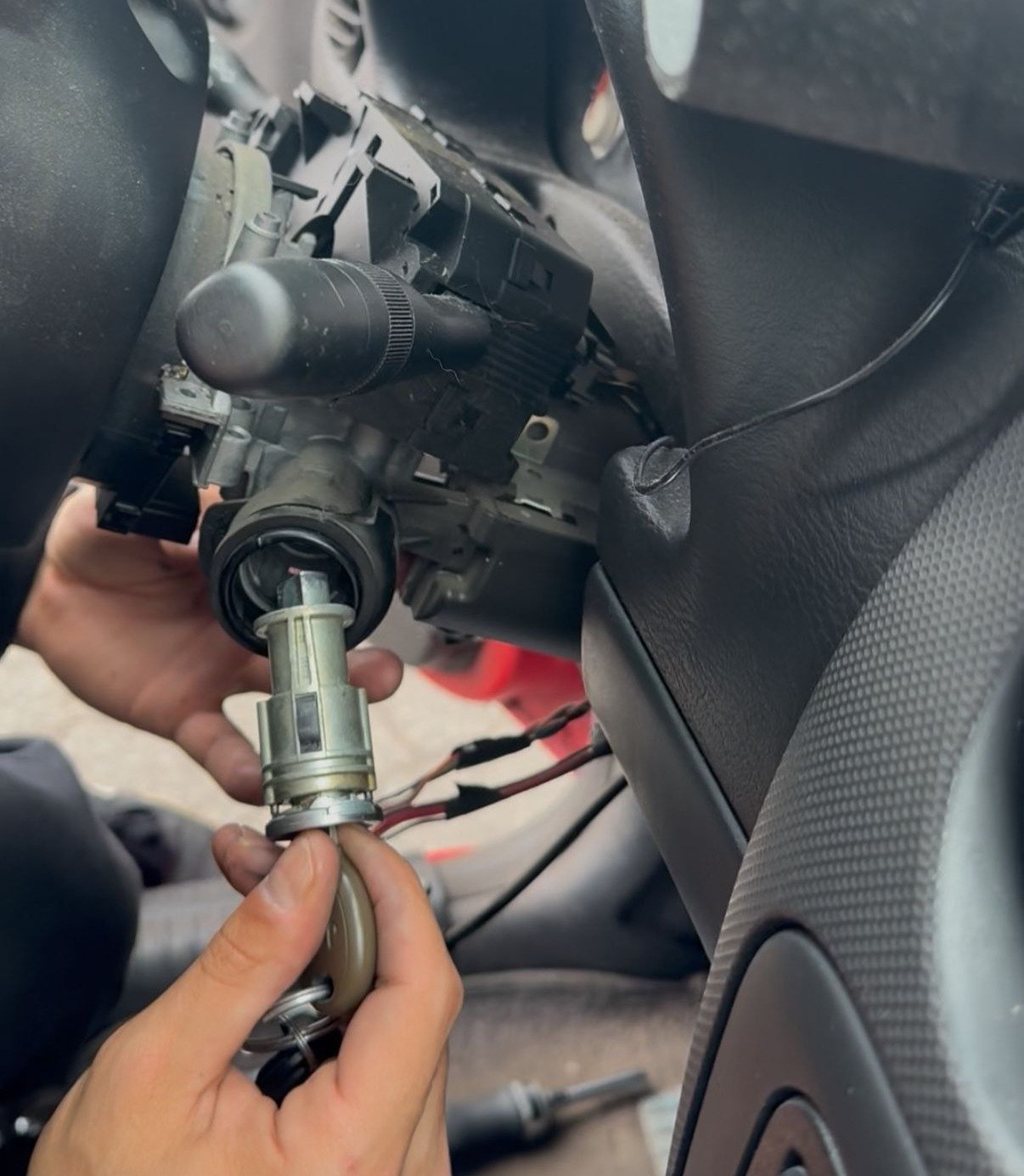 Mobile locksmith pulling a damaged ignition cylinder out of a steering column during a key not turning repair in San Diego